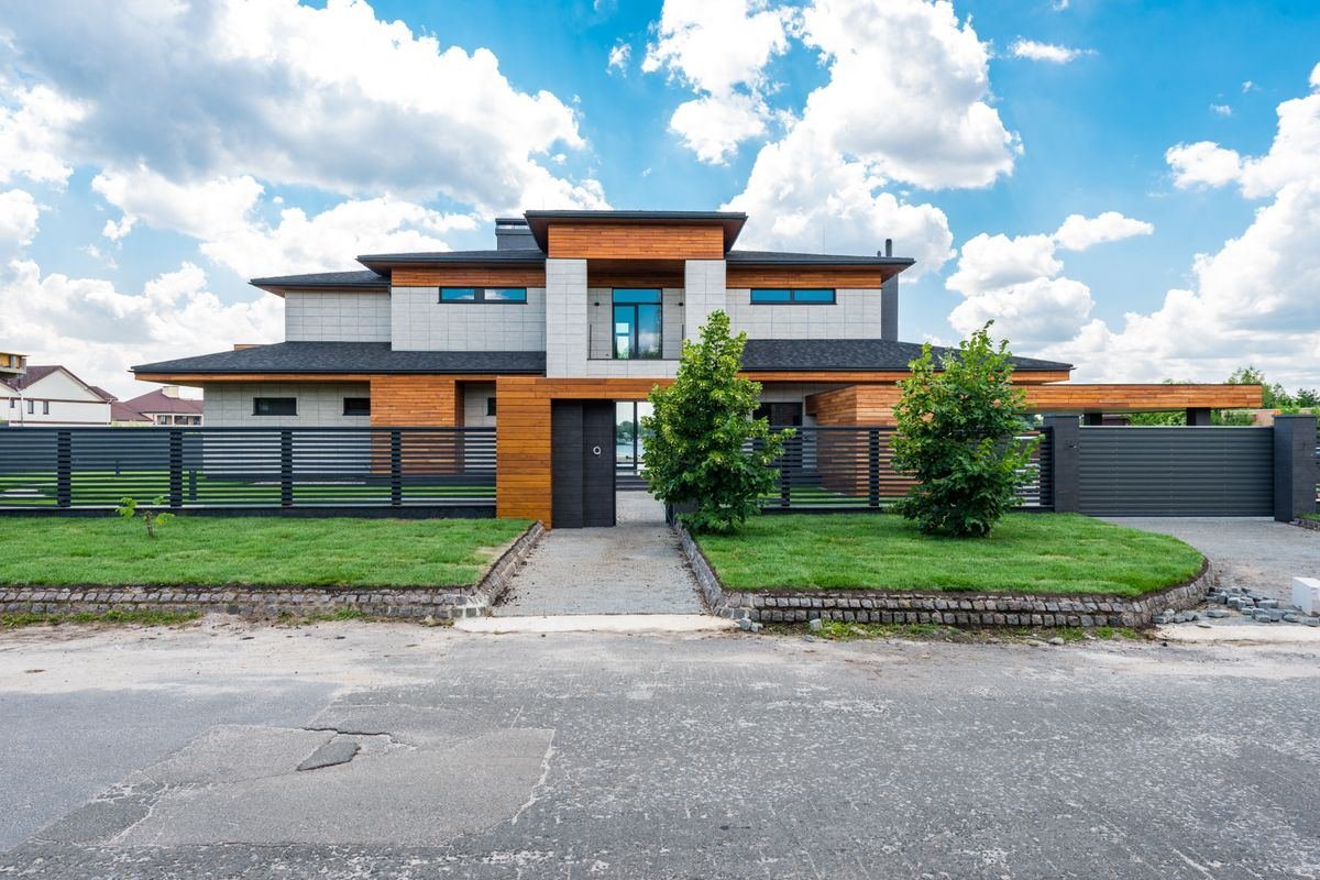A modern two-storey house with a front lawn and a gated driveway